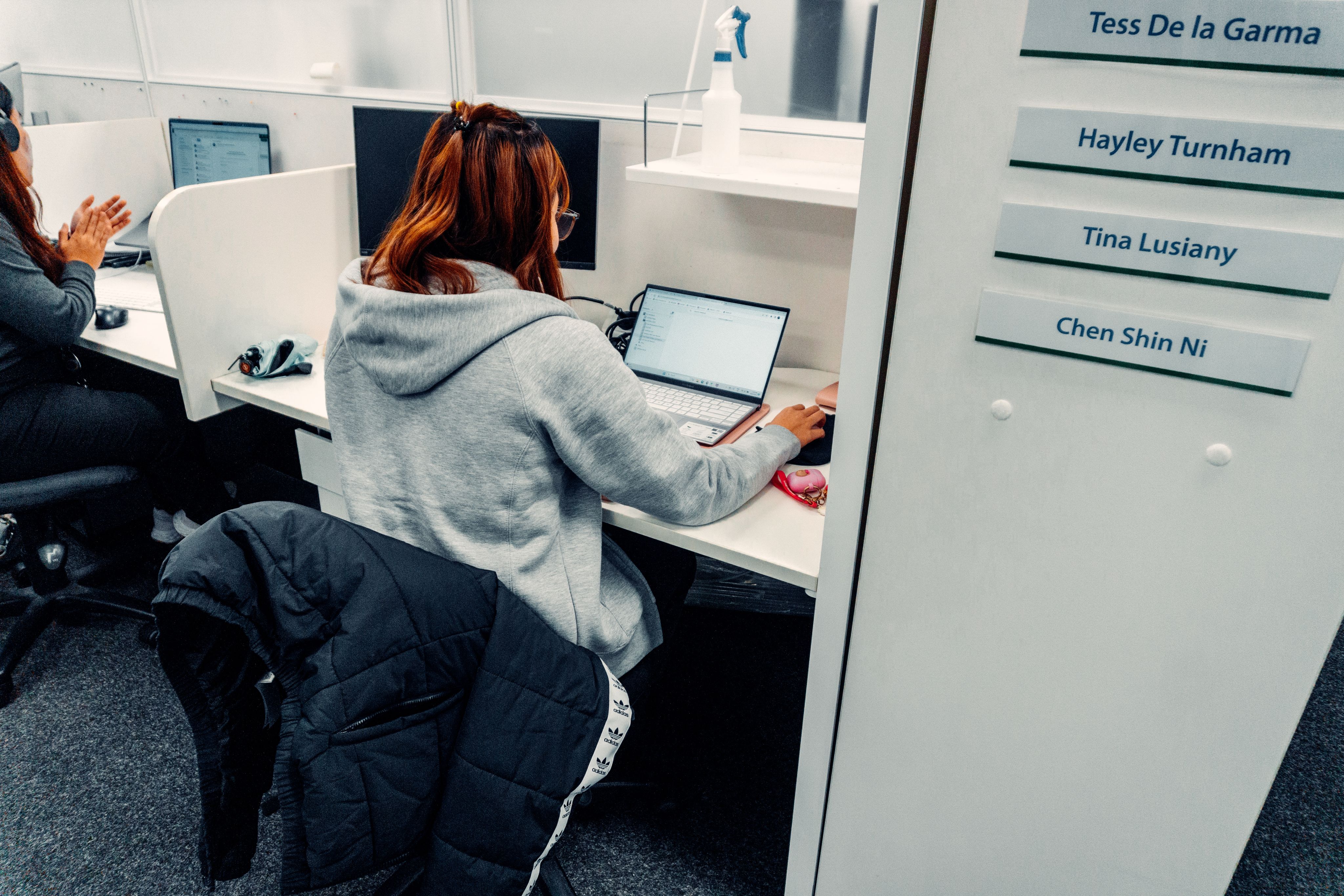 A young woman is captured sitting at her desk looking at her computer.