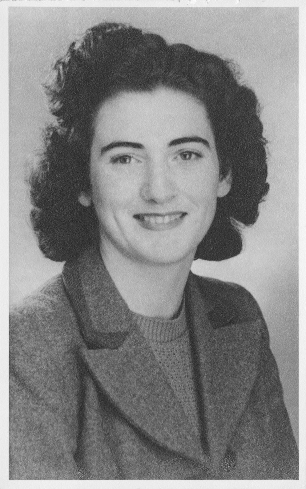 A black and white closeup shot of a young woman smiling directly at the camera.